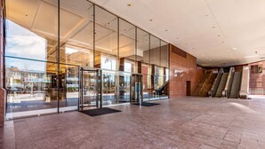 A spacious lobby with a glass entrance, escalators, and a tiled floor. - The Buckingham Hotel (Chicago)