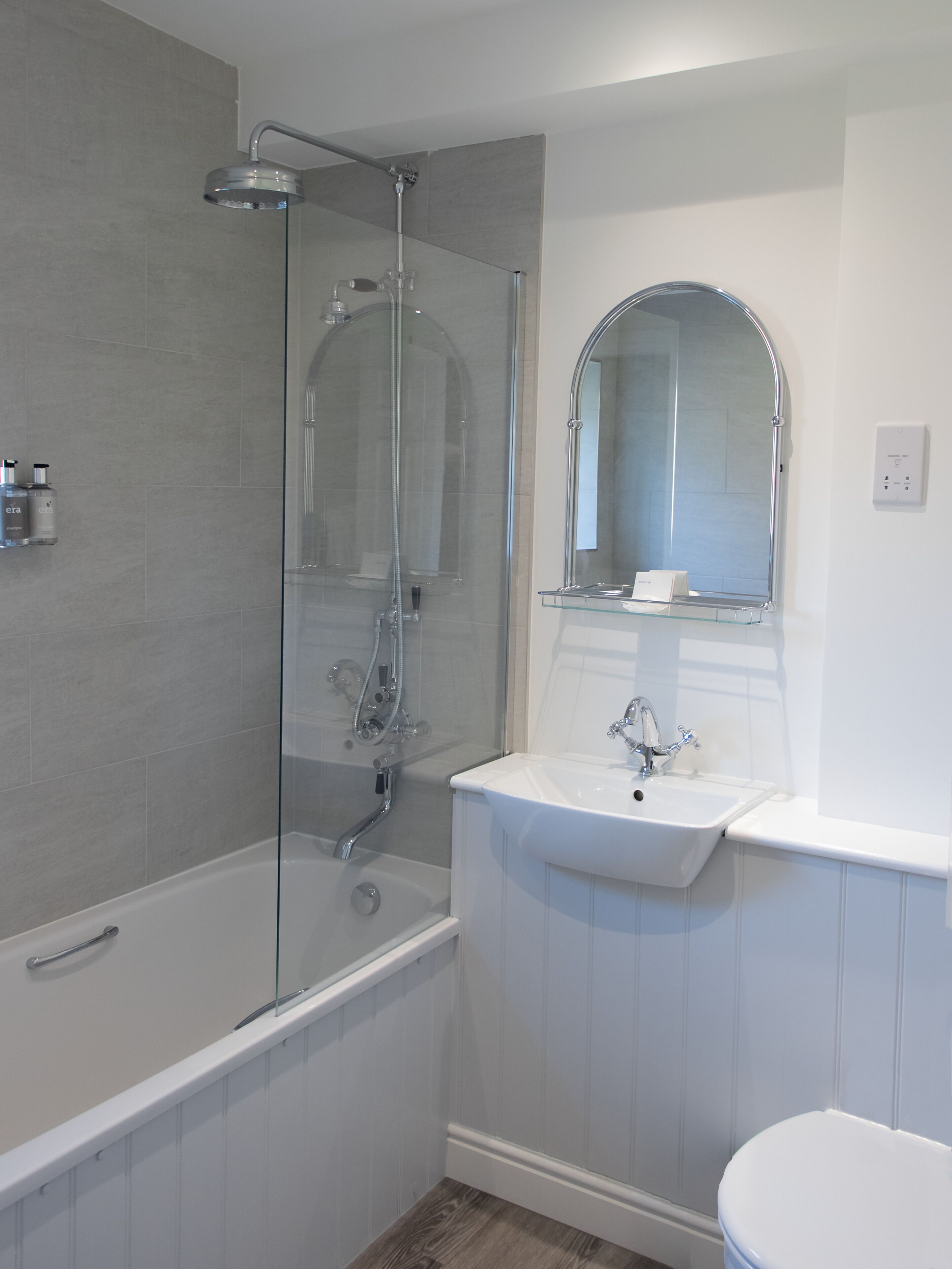 A modern bathroom with a glass-enclosed shower, a white sink, and a toilet.