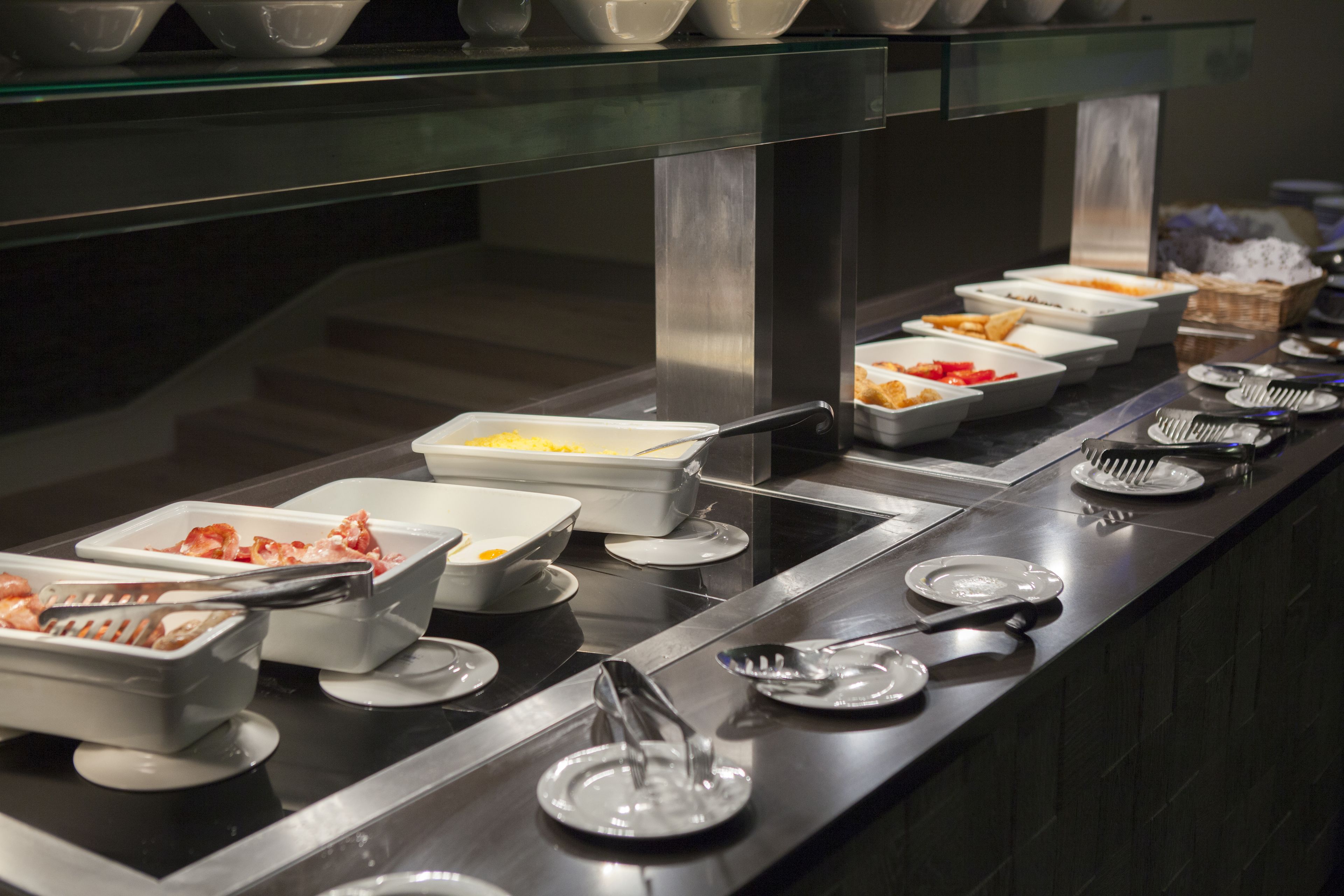 A buffet setup with various food containers and utensils.