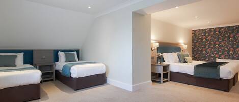 A hotel room with two beds, a desk, and a nightstand.