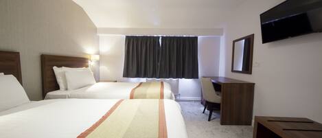 A hotel room with two beds, a desk, a chair, a TV, and a window with curtains.