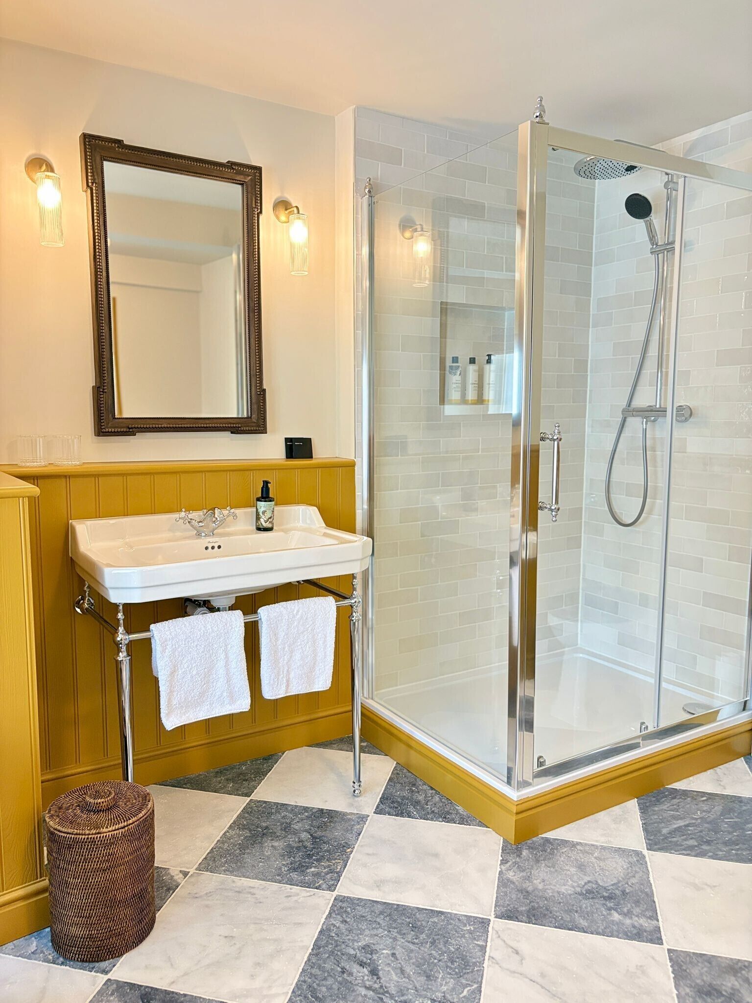 A bathroom with a glass-enclosed shower, a sink with a mirror above it, and a towel rack.