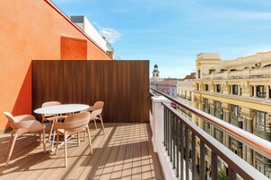 Ein Balkon mit Holzboden, einem weißen runden Tisch und vier Stühlen.