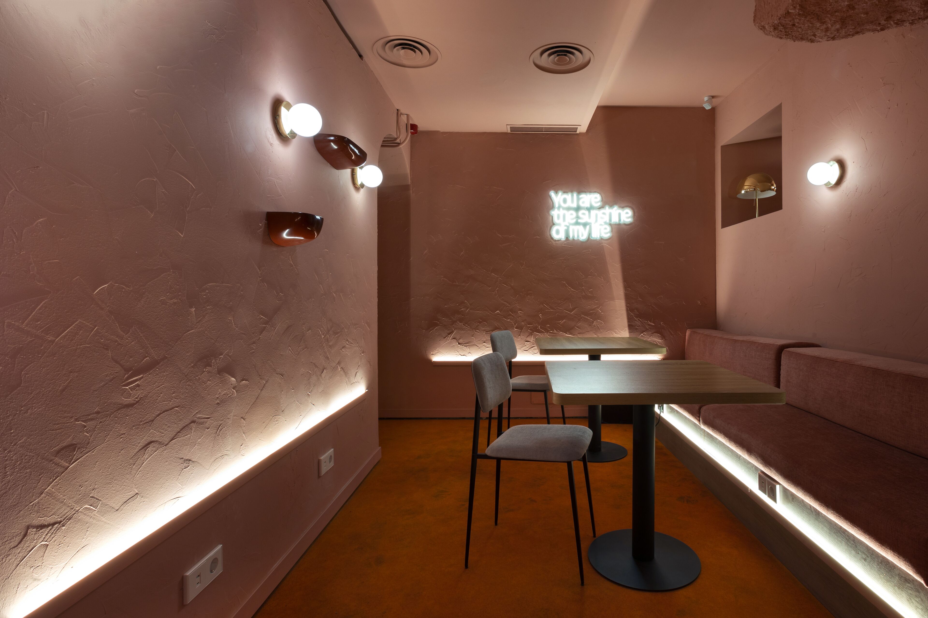 A modern interior with a table and chairs, a bench, and wall-mounted lighting.