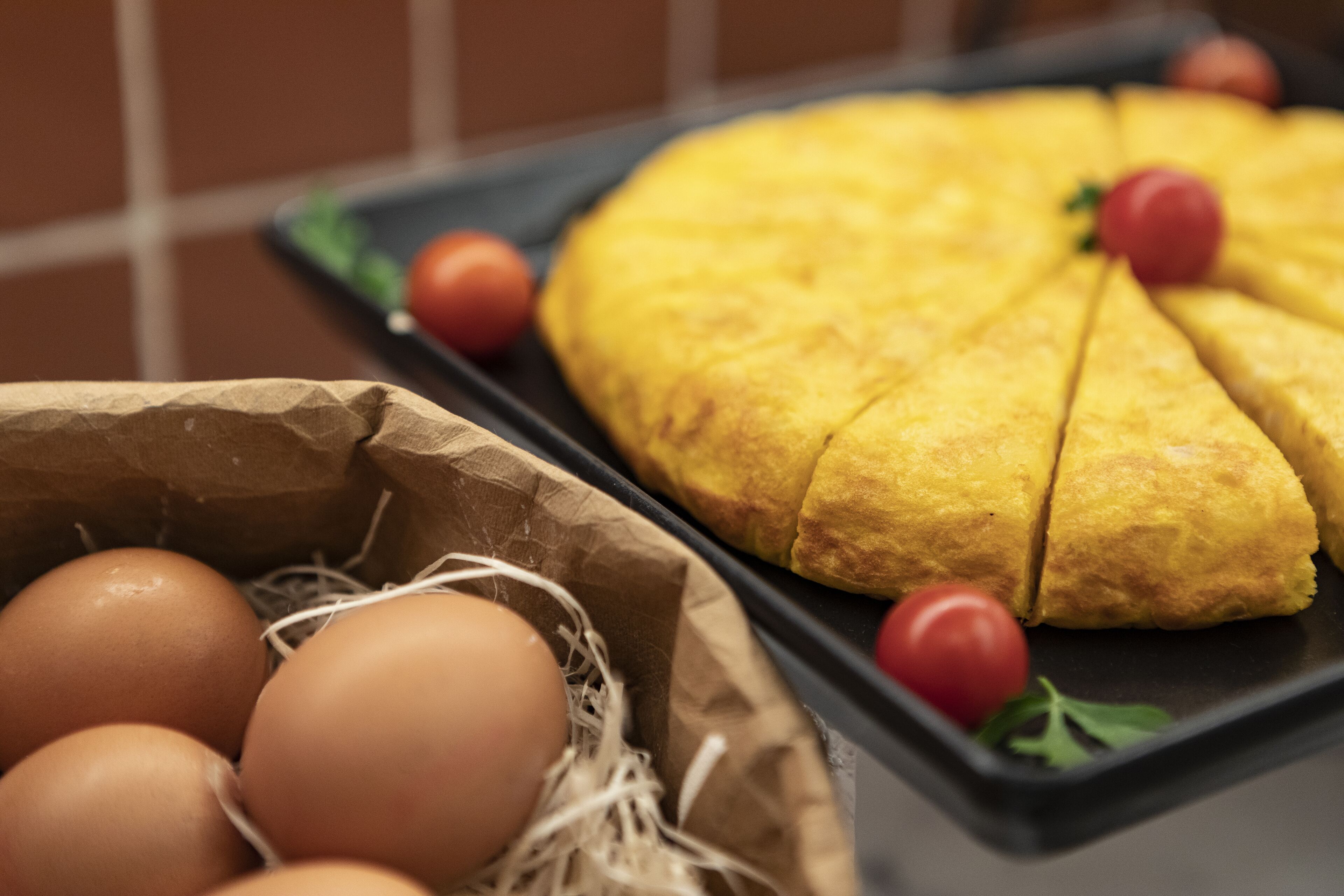 A kitchen counter with a loaf of bread, eggs, and tomatoes.