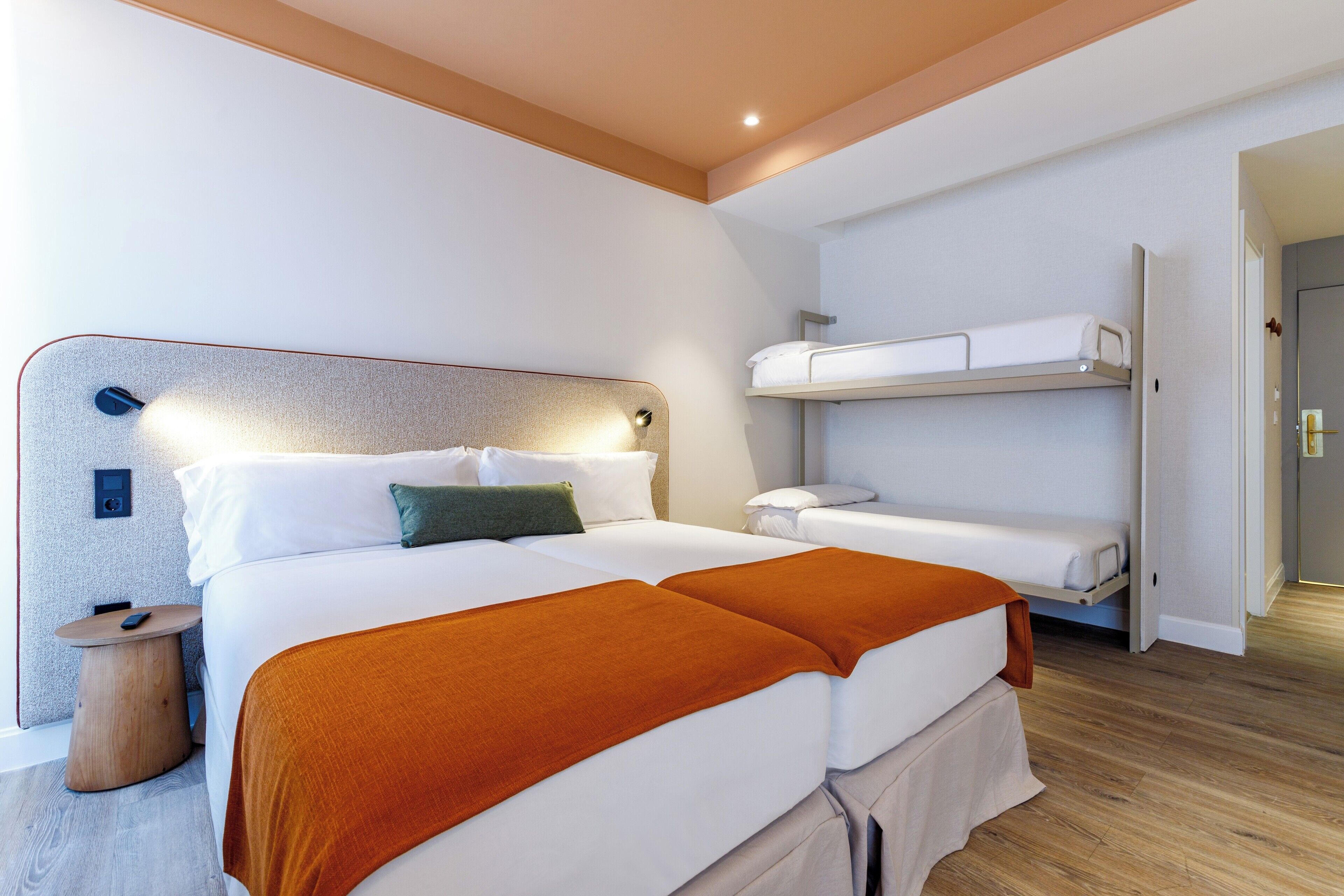 Een moderne hotelkamer met een groot bed, een nachtkastje en een ingebouwde bank boven het bed.
