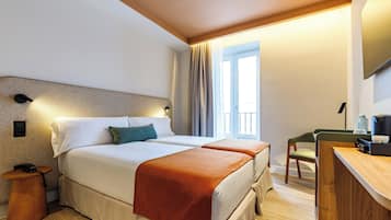 A hotel room with a large bed, bedside tables, a desk, and a television.