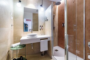 Ein modernes Badezimmer mit einer Duschkabine aus Glas, einem weißen Waschbecken und einem Spiegel darüber.