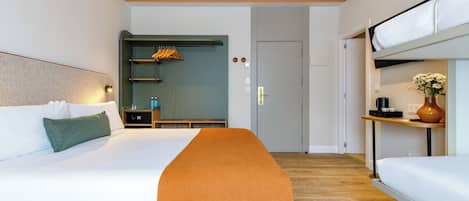 Una habitación de hotel moderna con una cama grande, un banco, una mesita con un jarrón y una cama litera.