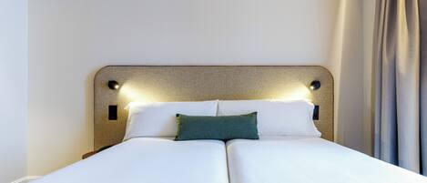 Una cama doble con cabecera, dos almohadas y una mesita de noche.