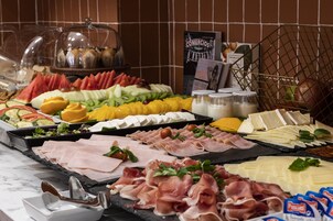A buffet with various food items including meats, cheeses, fruits, and vegetables.