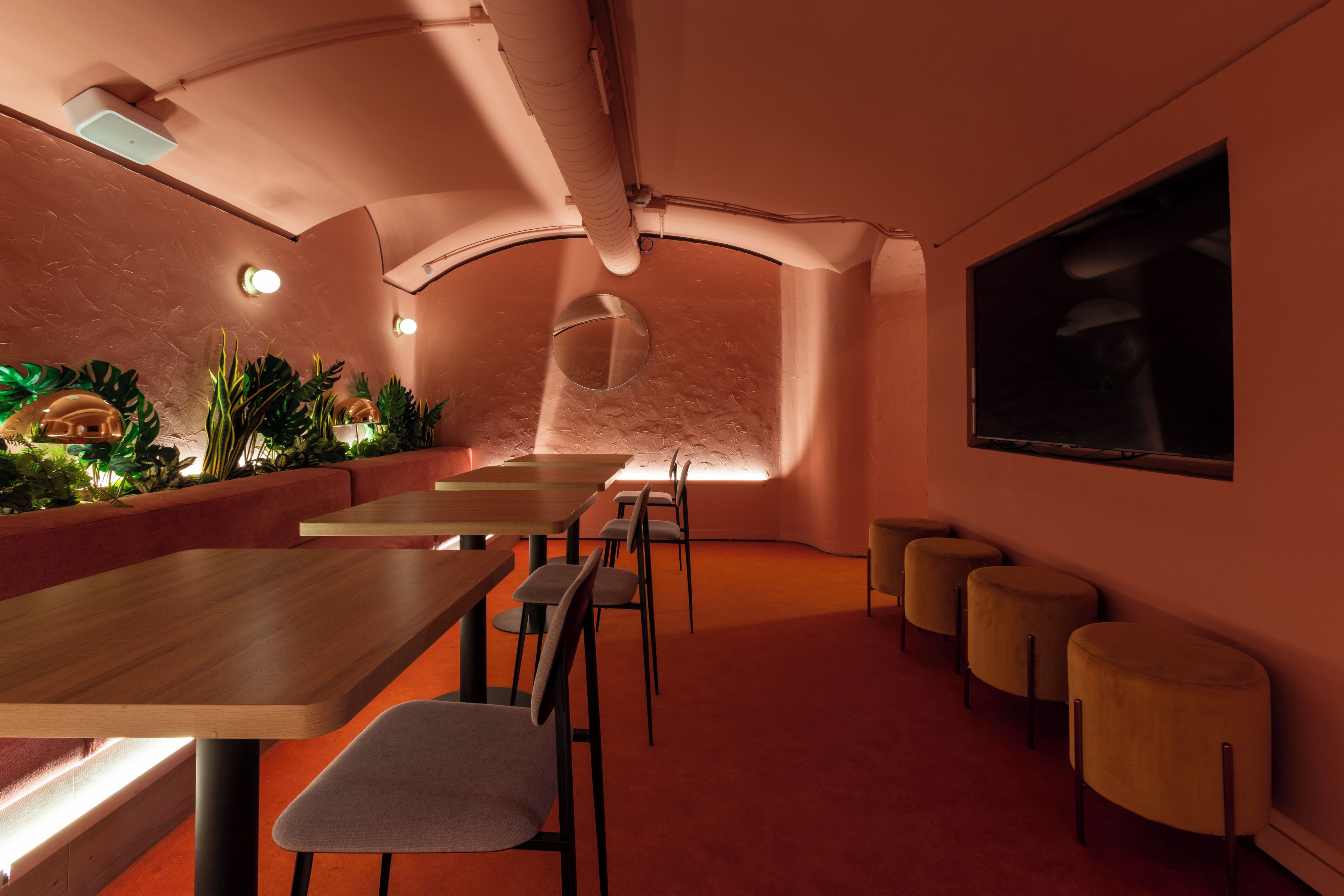 A modern interior with a long table, chairs, and a large screen on the wall.