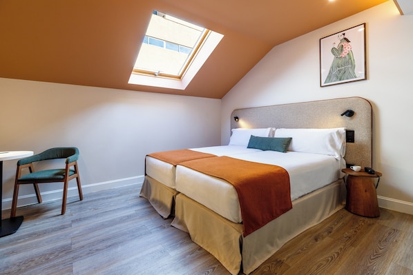 A bedroom with a skylight, a bed with a headboard, a bedside table, a chair, and a wooden floor. - Petit Palace Puerta del Sol (Madrid)
