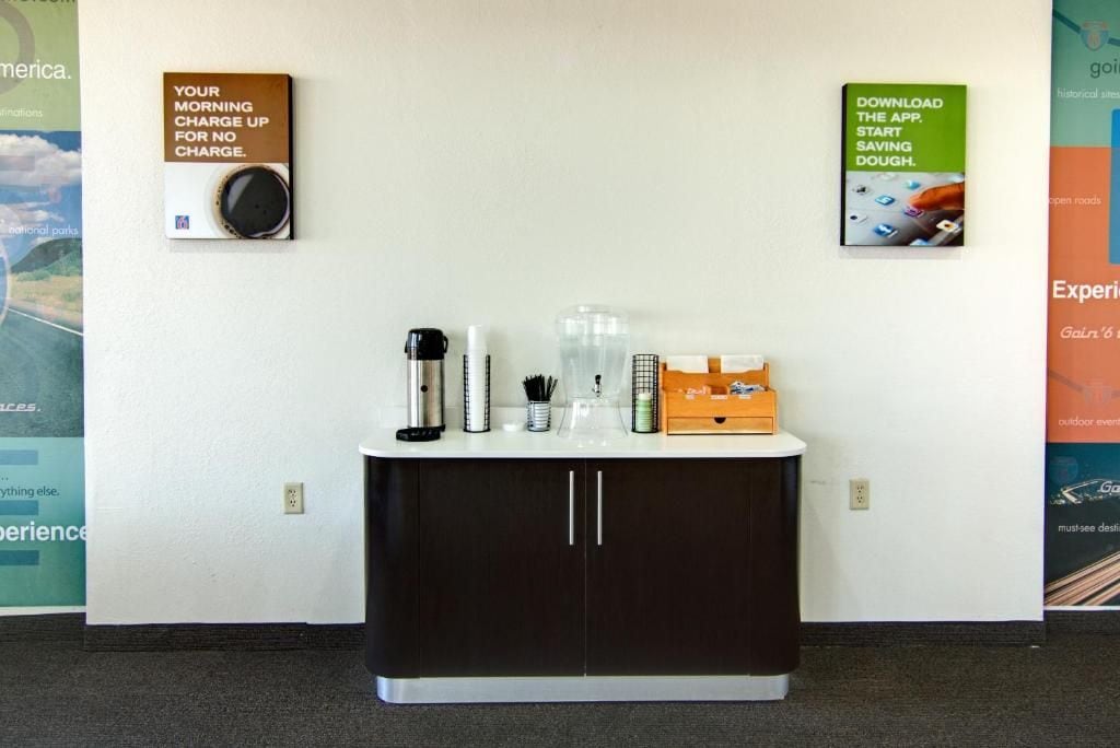 A reception desk with a coffee maker, water bottle, and a box of tissues.