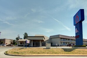 Un motel con un grande cartello con il numero '6', un parcheggio e un edificio con tetto piatto.