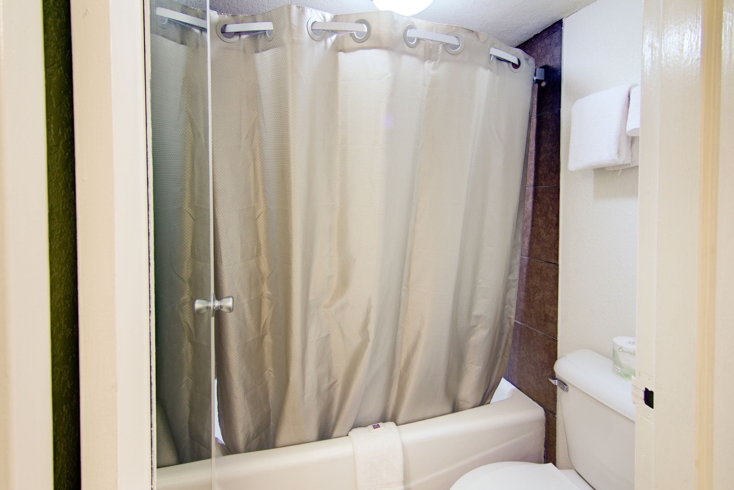 Un baño con cortina de ducha, inodoro y perchero para toallas.