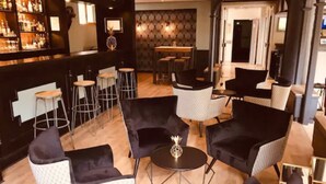 Un espace bar comprenant un comptoir, des tabourets et un coin salon avec des chaises et des tables.