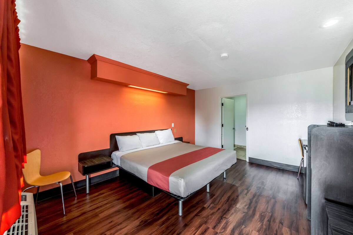 Una habitación de hotel con una cama, una silla, un escritorio y un kitchenette.