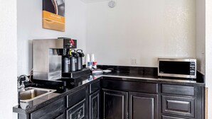 A modern kitchen with a stainless steel sink, a coffee machine, and a microwave.