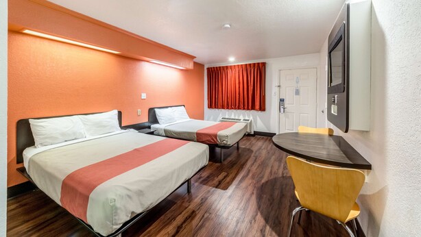 A hotel room with two beds, a dining table, and a chair.