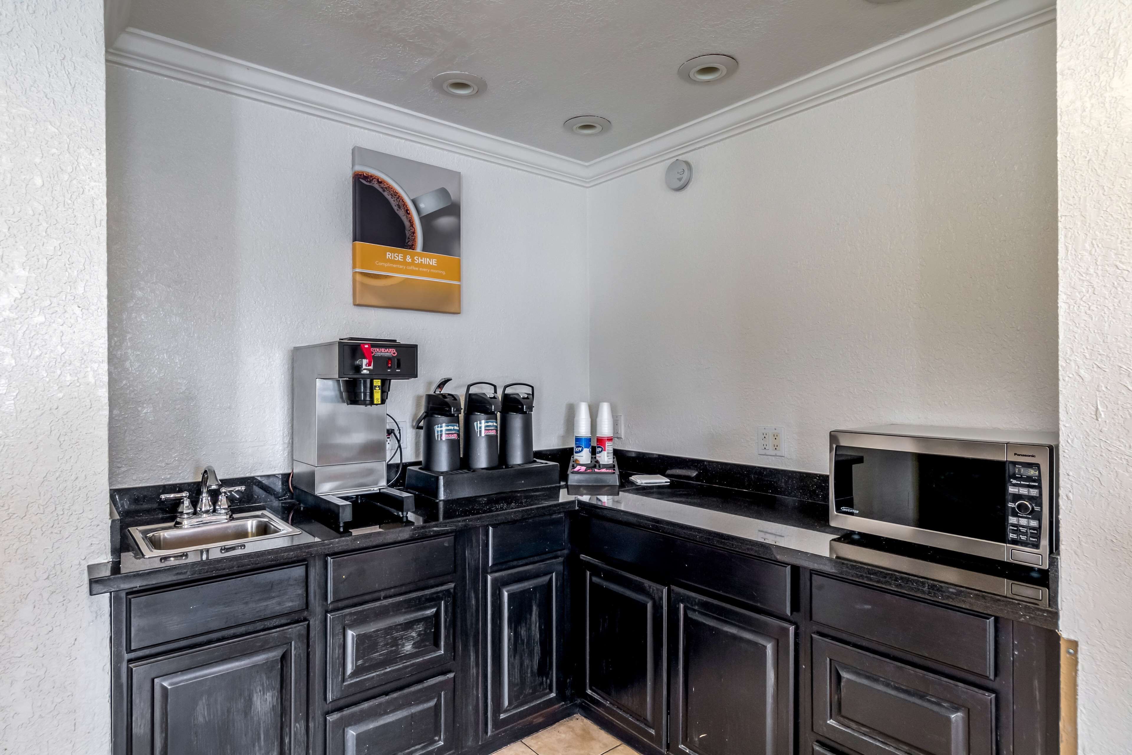 A compact kitchen with a sink, coffee makers, and a microwave.