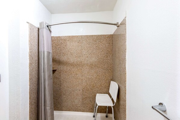 Un área de ducha con cortina, una silla blanca y un perchero.