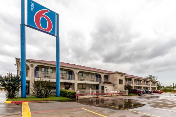 Un motel con un gran letrero azul, varios balcones y un estacionamiento.