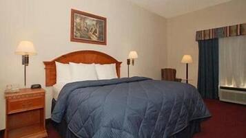 Habitación de hotel con una cama grande, dos mesitas de noche con lámparas, un aparador, un cuadro en la pared y una ventana con cortinas.