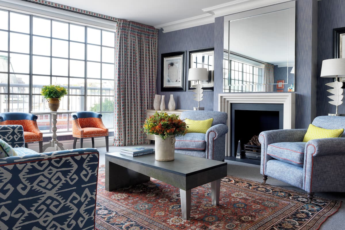 A living room with a fireplace, patterned rug, and two armchairs.