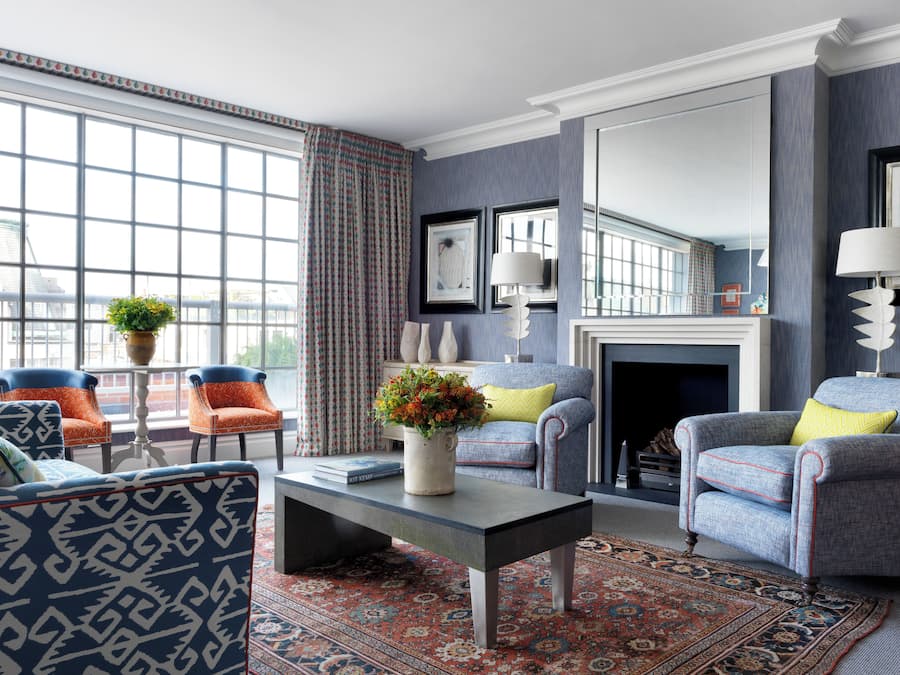A living room with a fireplace, patterned rug, and two armchairs.