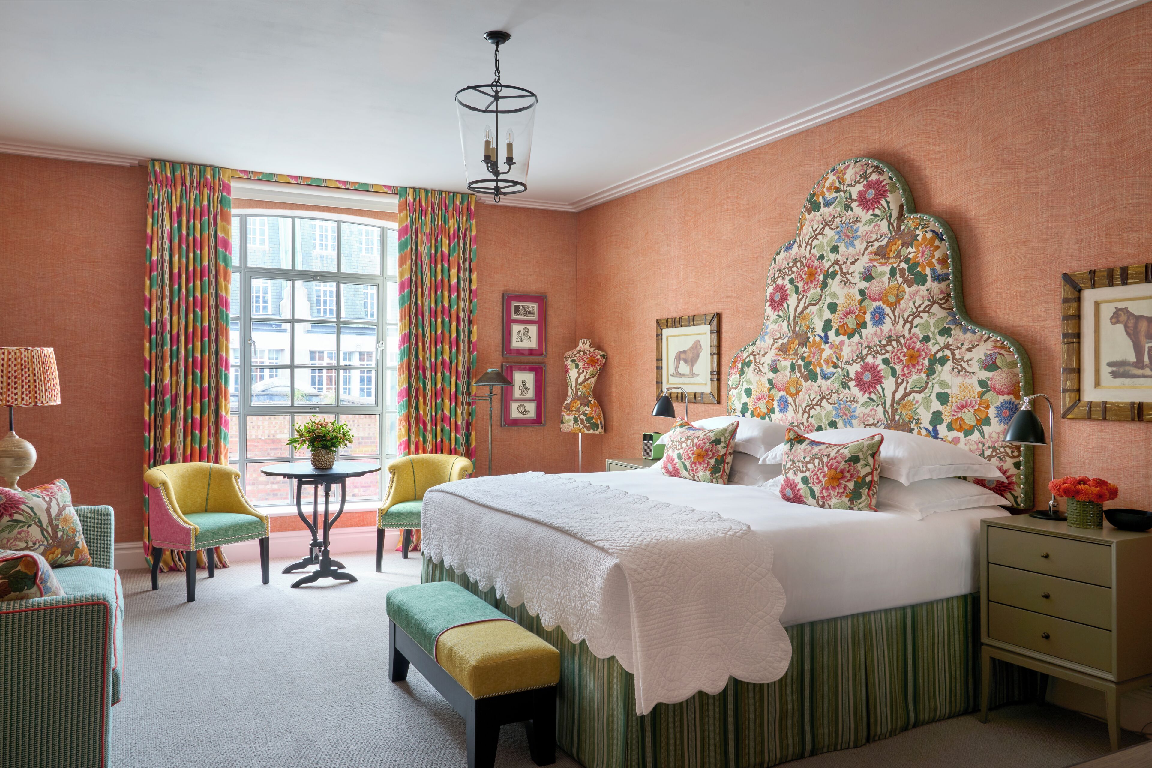A bedroom with a large bed, a chair, a small table, and a bench.