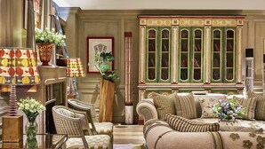 Un salon traditionnel avec un canapé, des fauteuils, une bibliothèque et un tapis à motifs.