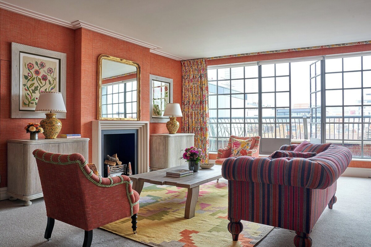 A living room with a fireplace, striped sofas, and a large window with a view.