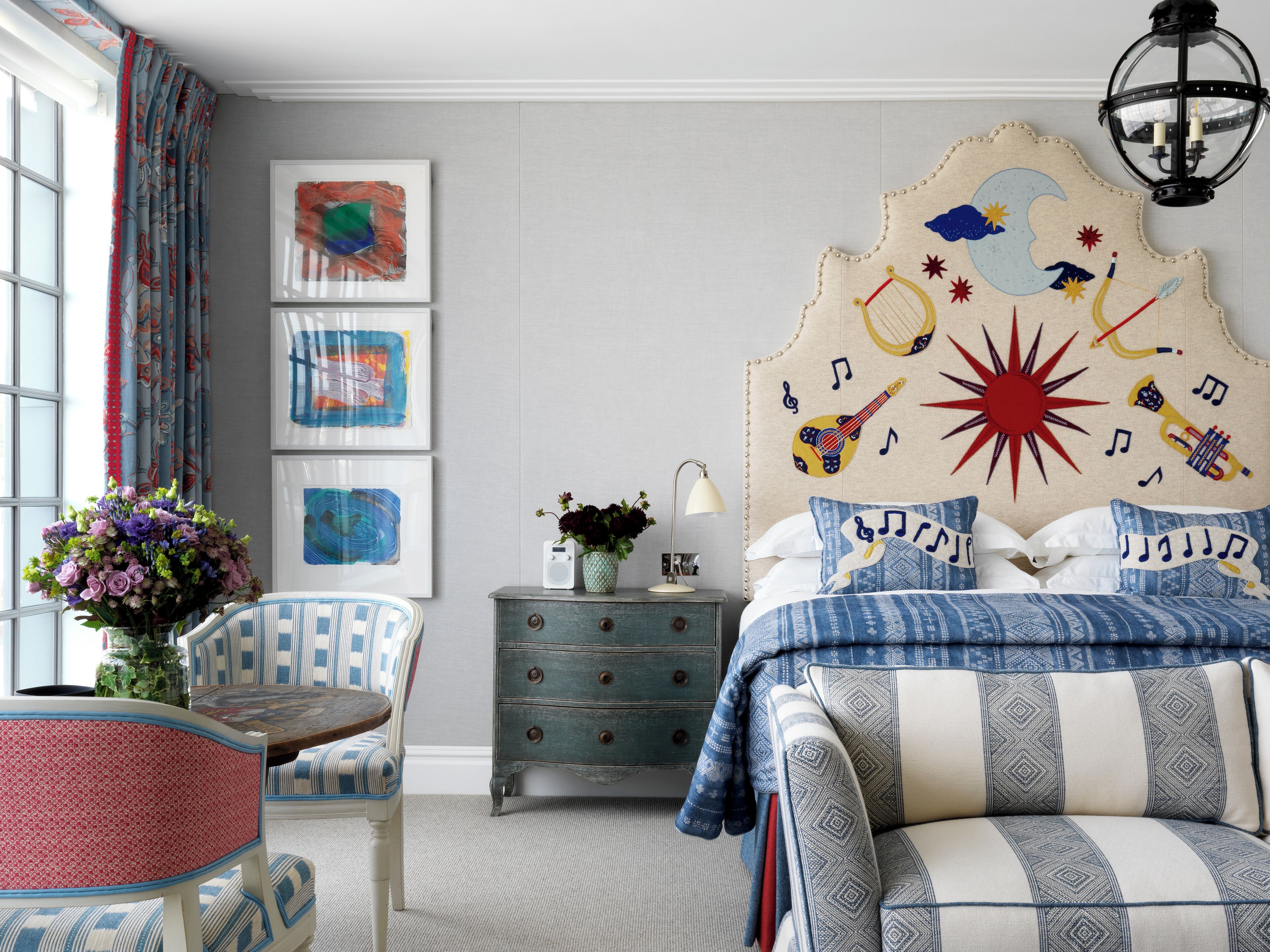 A bedroom with a striped sofa, a chair, a dresser, and a headboard with musical notes and instruments.