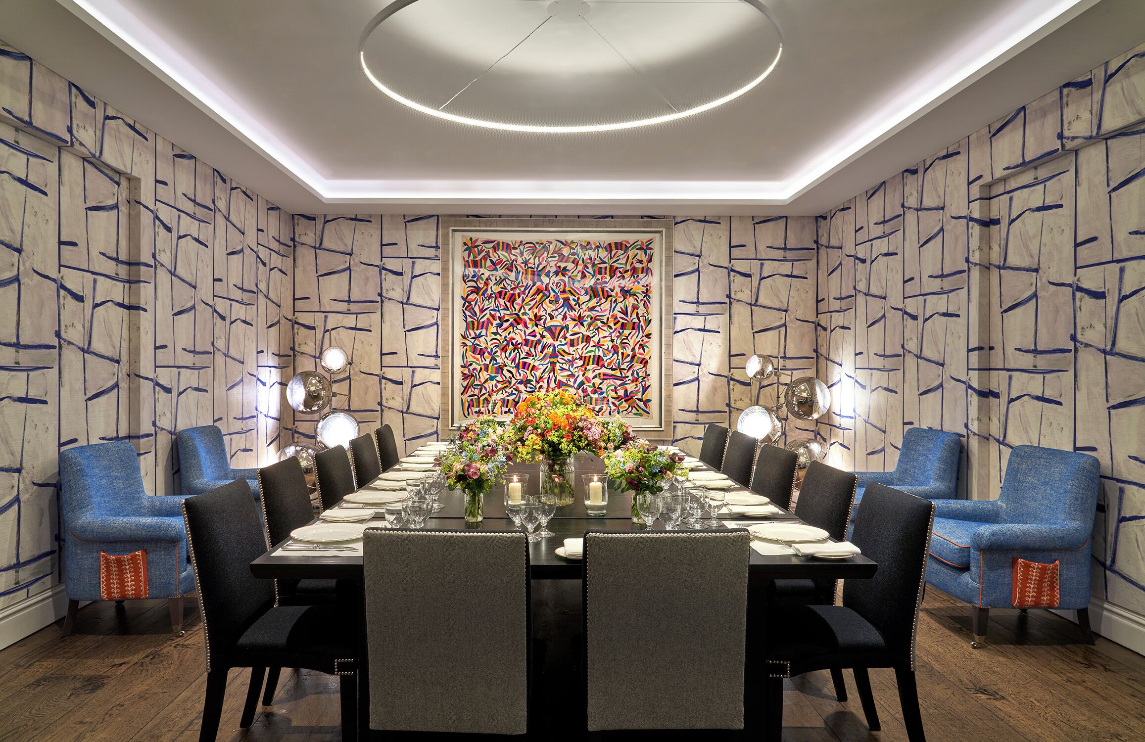 Uma sala de jantar com uma mesa comprida posta para seis pessoas, rodeada por cadeiras estofadas azuis.