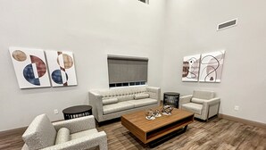 Un salon moderne avec un canapé, des fauteuils, une table basse et des œuvres d’art abstraites accrochées aux murs.
