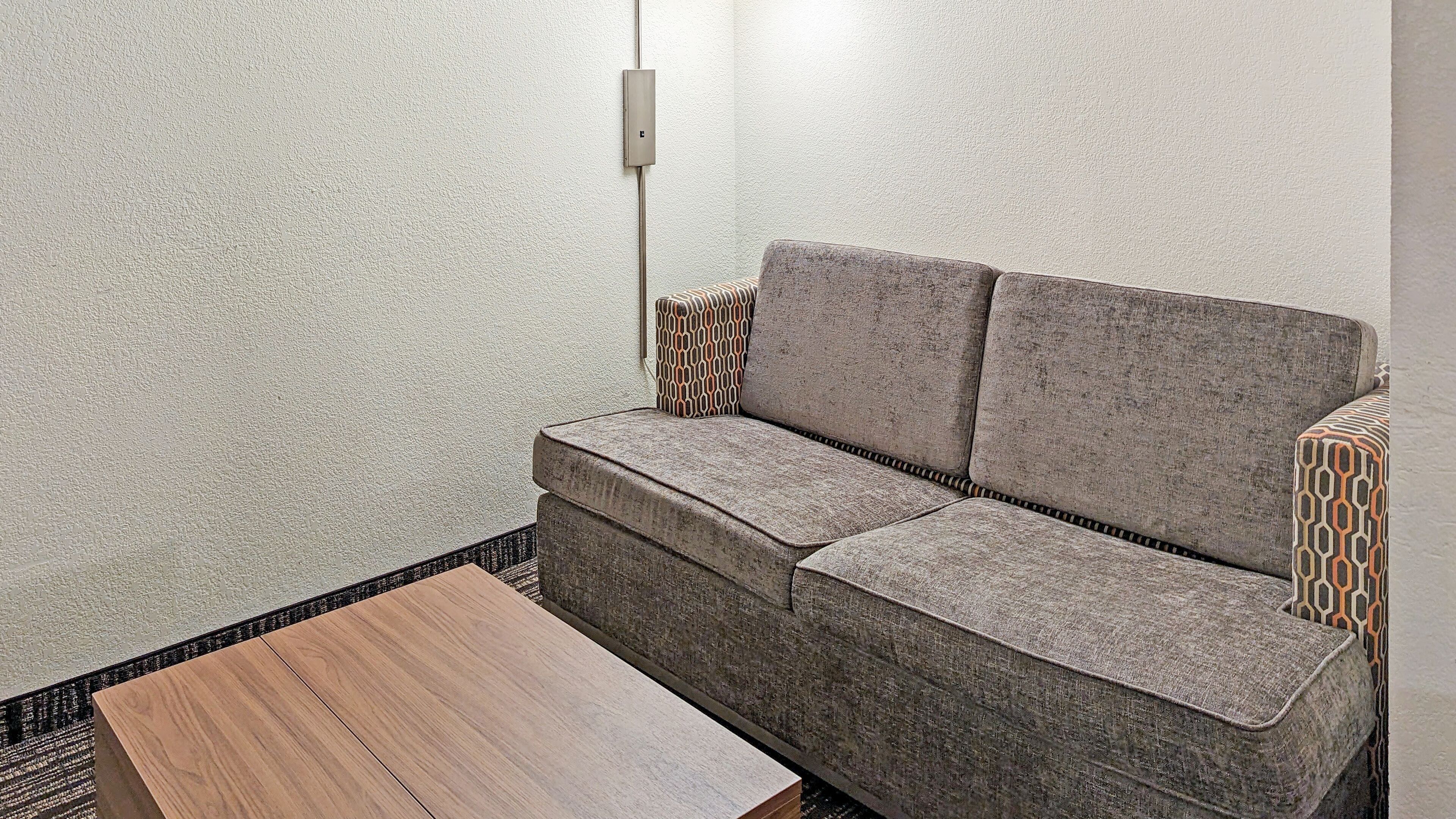 Une pièce moderne avec un canapé gris, des coussins à motifs et une table en bois.