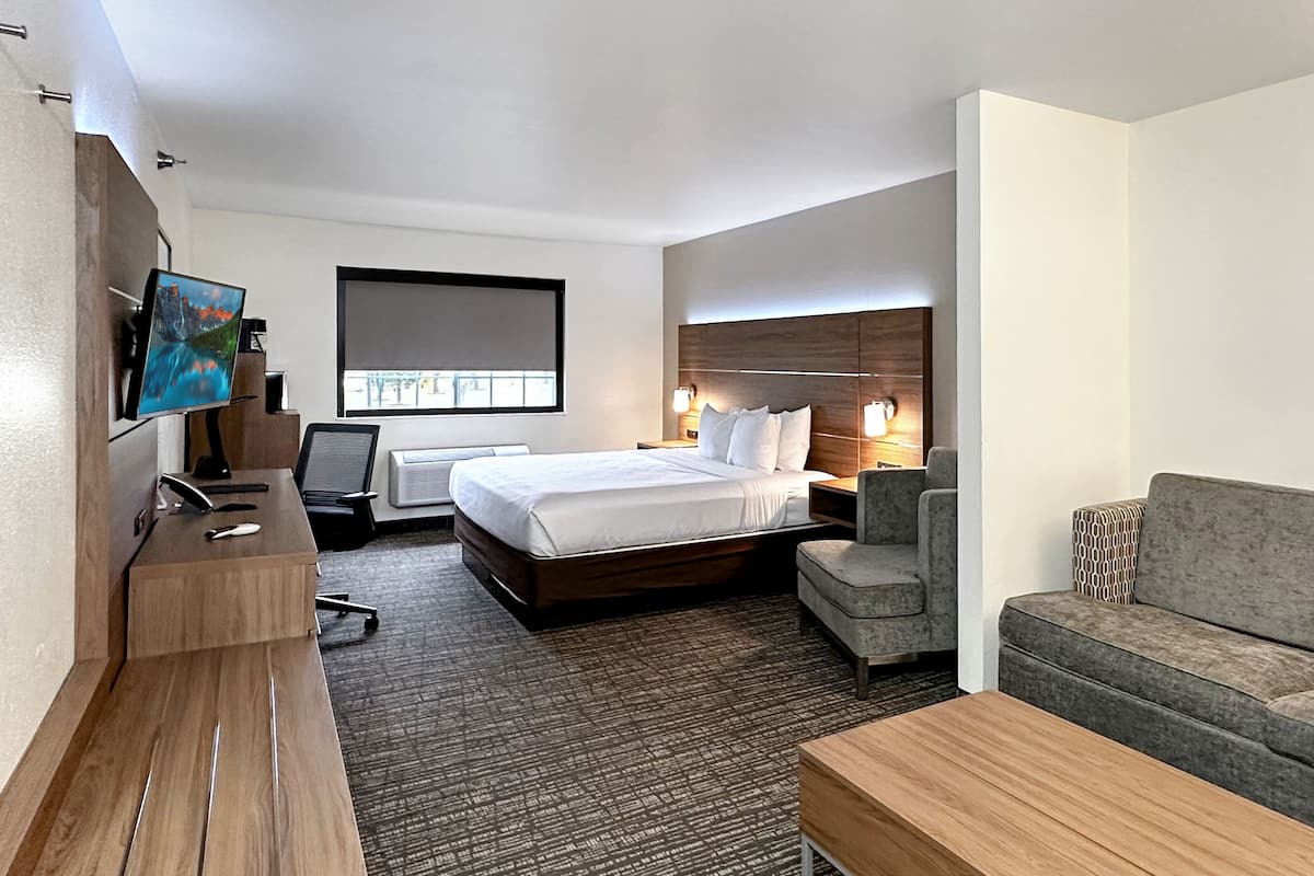 Een hotelkamer met een bed, een bureau, een televisie, een bank en een salontafel.