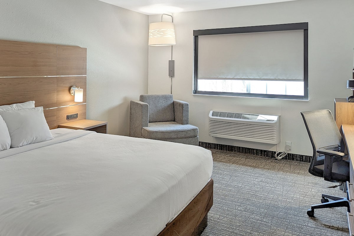 Een hotelkamer met een groot bed, een stoel, een bureau en een raam met uitzicht.