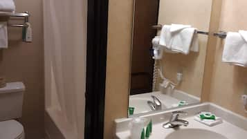 A bathroom with a white sink, mirror, and shower curtain. There are towels on the wall and a toilet visible.