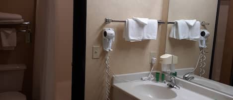A bathroom with a white sink, a mirror, a hairdryer, and a shower curtain.