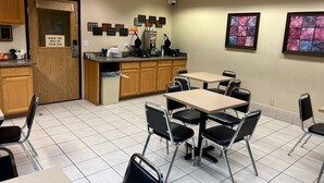 Une chambre d’hôtel équipée d’une kitchenette, d’un coin repas avec tables et chaises, et agrémentée d’œuvres d’art aux murs.