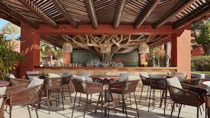 An outdoor bar area with wicker furniture and a wooden ceiling structure.