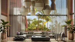 A spacious living area with a large sofa set, a coffee table, and hanging pendant lights.