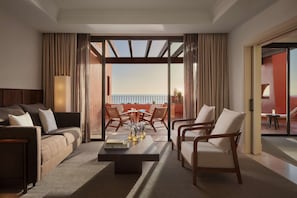 A modern hotel room with a sofa, armchairs, a coffee table, and a balcony with a view. - Tivoli la Caleta Resort (Adeje)