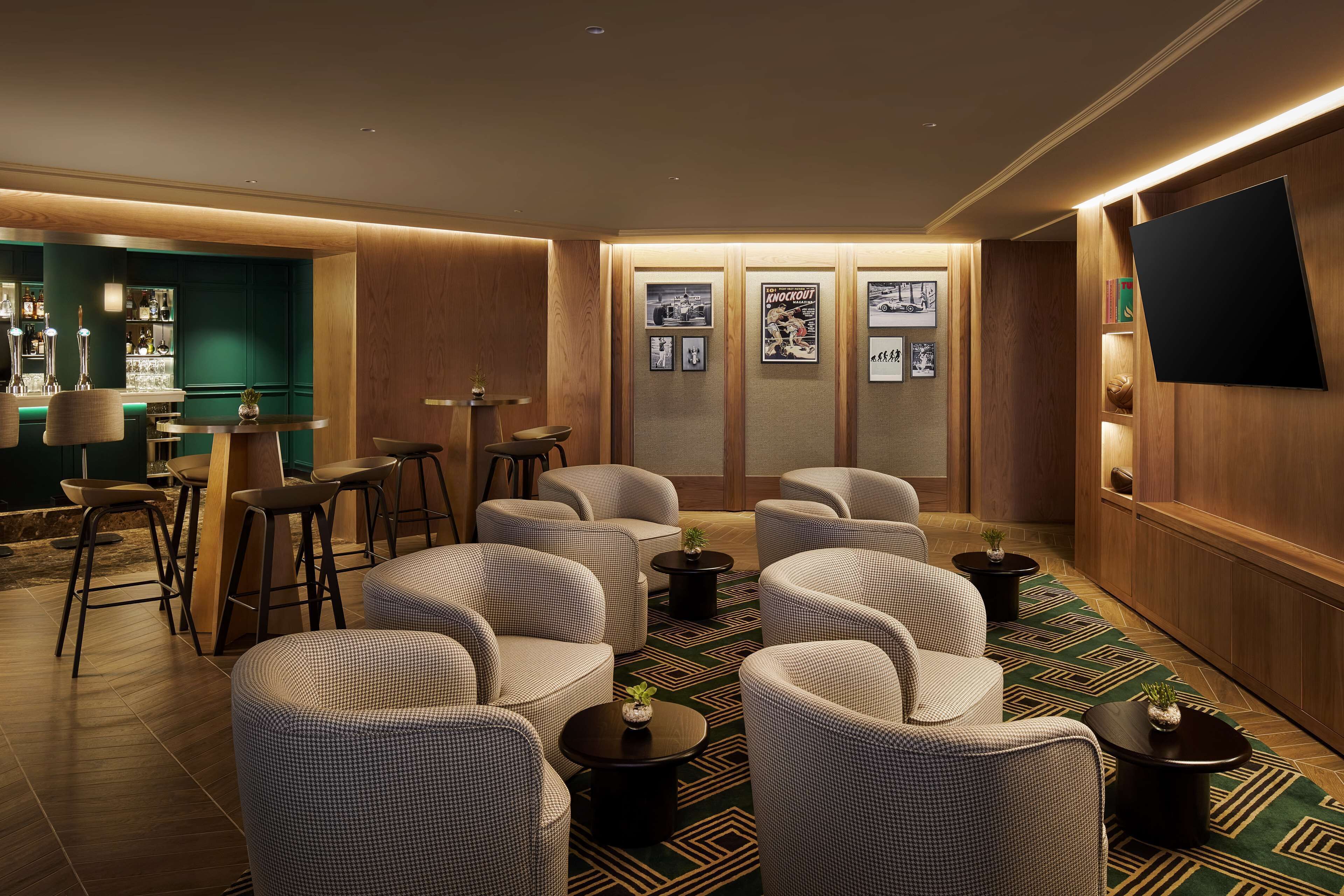 A modern lounge area with a bar, seating, and a flat-screen TV mounted on the wall.
