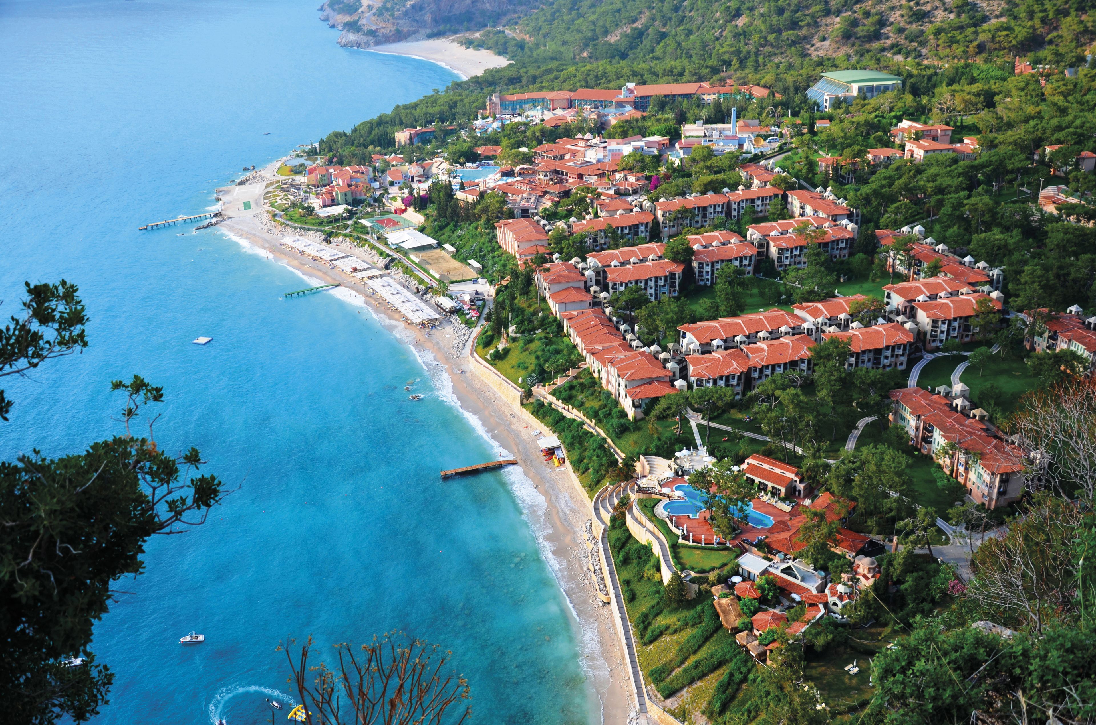 An aerial view of a coastal resort with multiple buildings, a beach, and a pier.