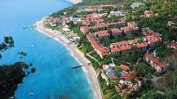 An aerial view of a coastal resort with multiple buildings, a beach, and a pier.