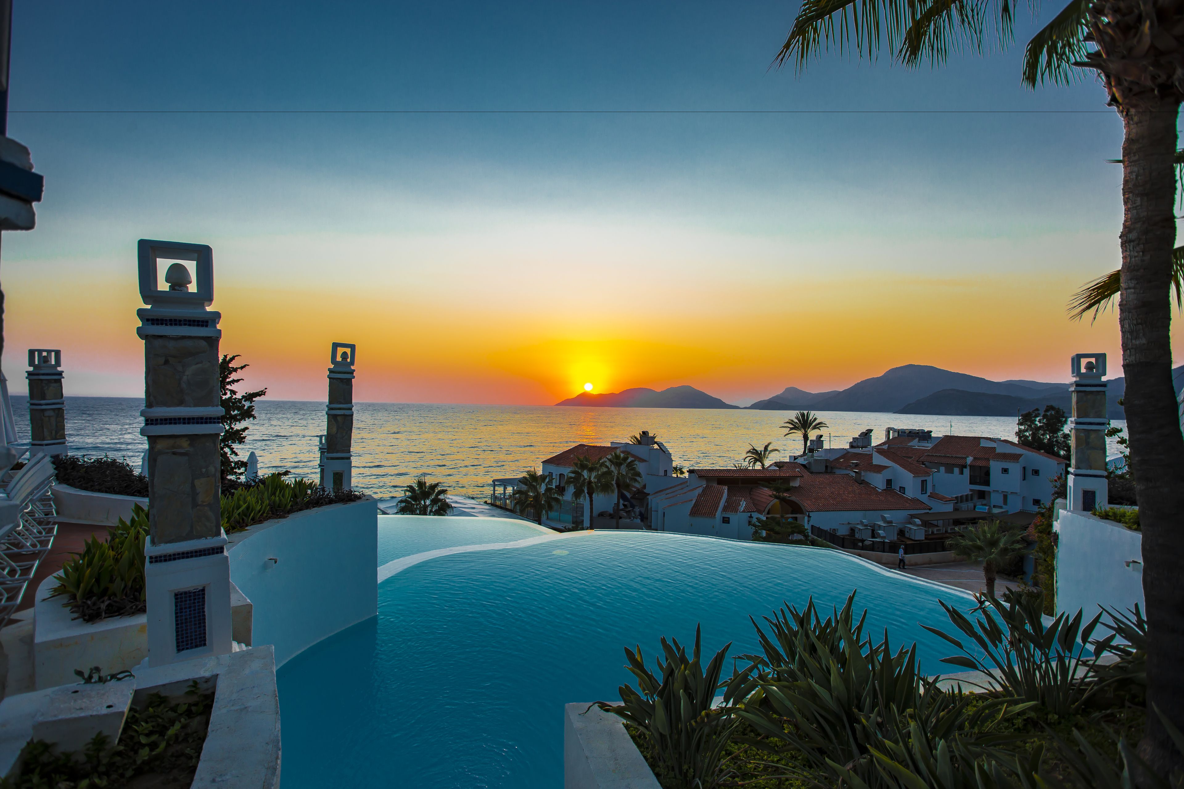 A resort with a pool, palm trees, and a sunset view.