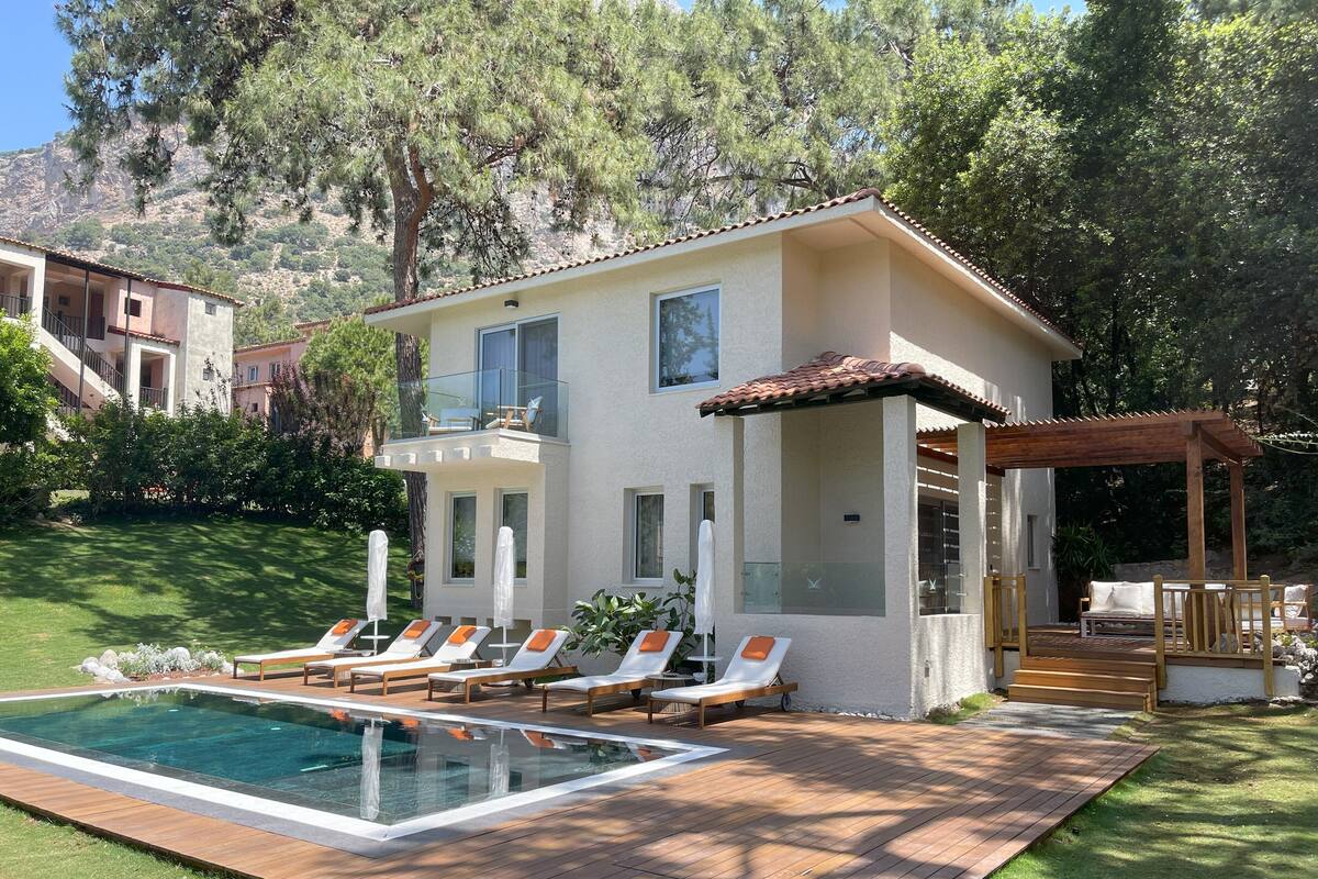 A two-story house with a pool, outdoor seating, and a pergola.